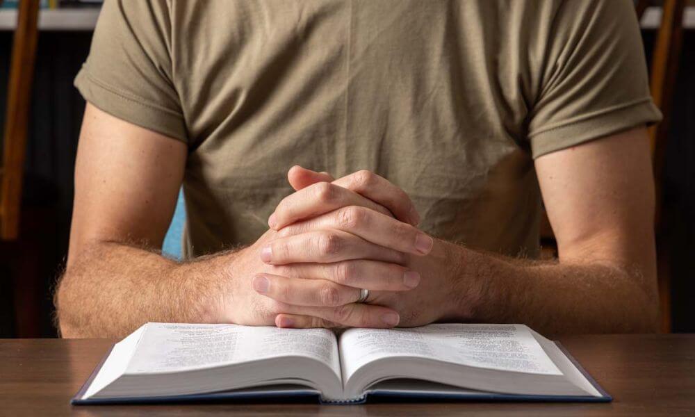 A man in chaplaincy school praying with a bible